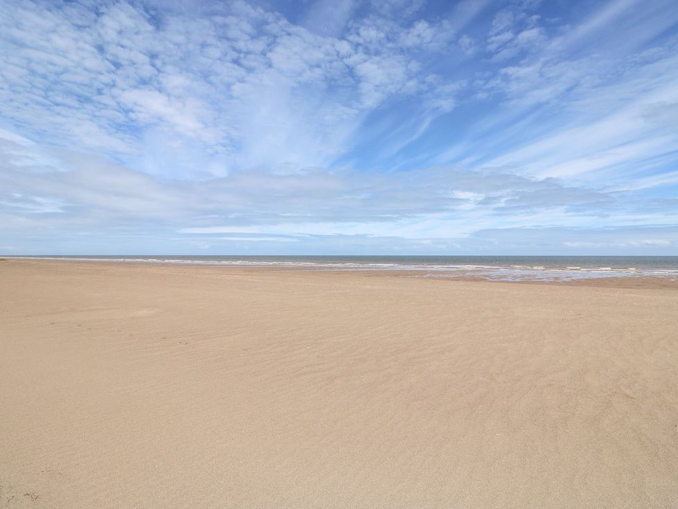 An empty beach with sand and ocean under a cloudy sky at The Seaside Retreat in Mablethorpe