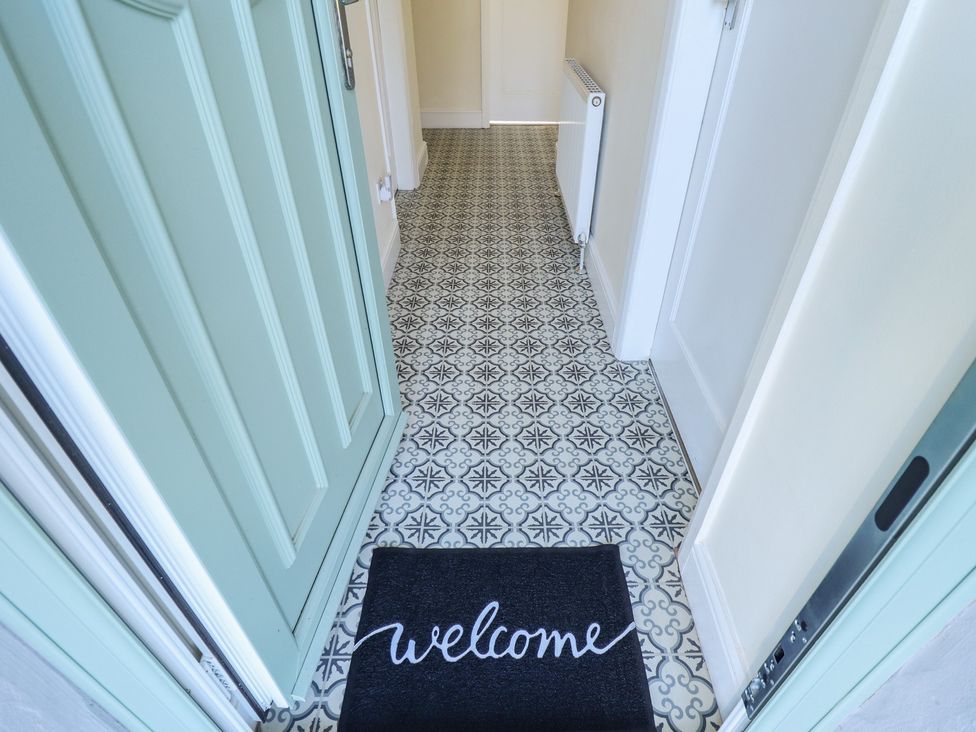 A hallway with a front door and welcome mat at The Seaside Retreat in Sutton-On-Sea