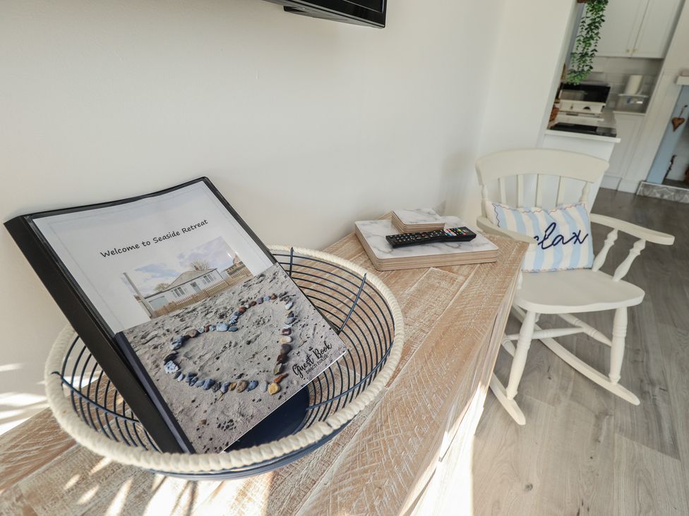 A living room with a welcome book and remote control at The Seaside Retreat in Sutton-On-Sea