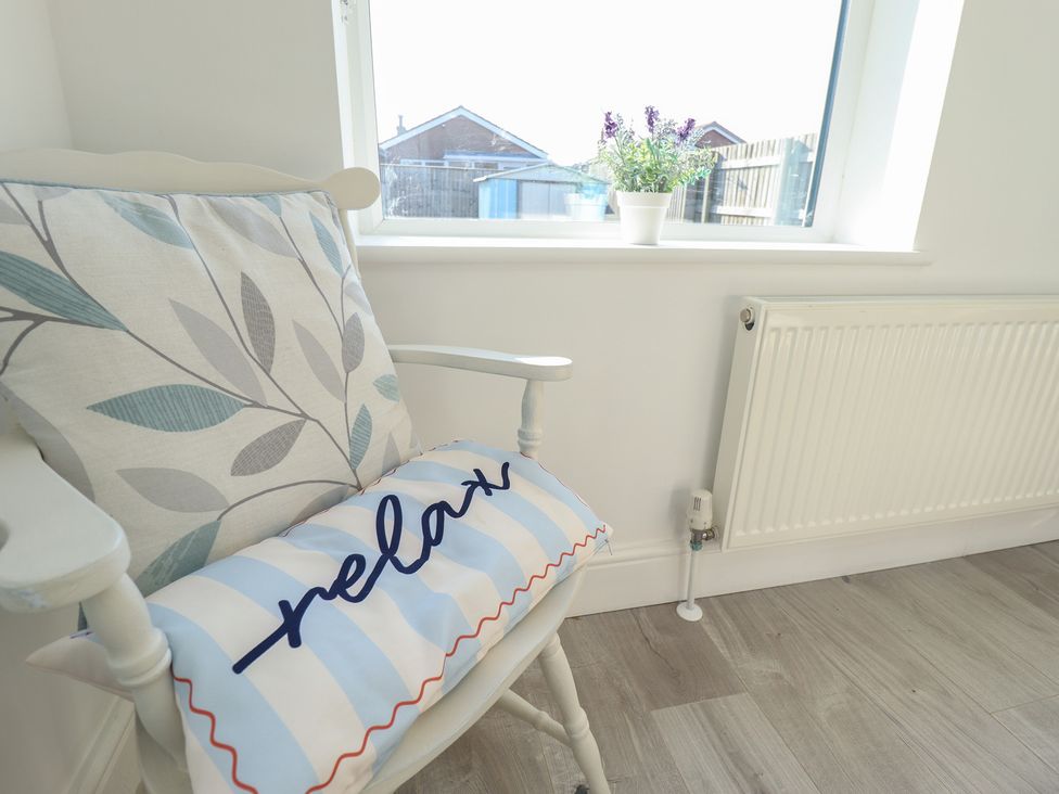 A snug with an armchair and a cushion at The Seaside Retreat in Sutton-On-Sea