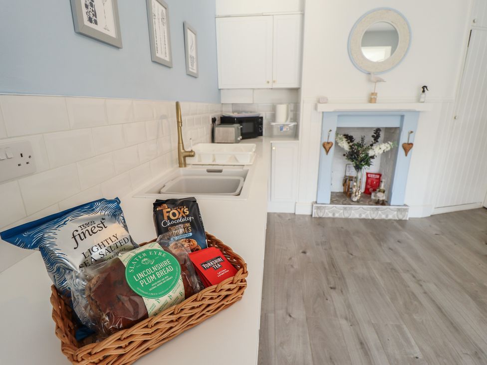 A kitchen with a sink and basket of snacks at The Seaside Retreat in Sutton-On-Sea