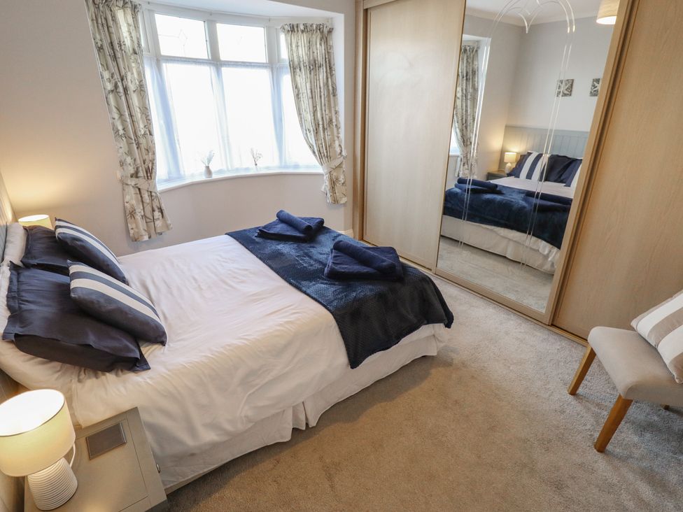 A bedroom with a bed and mirror at The Seaside Retreat in Sutton-On-Sea