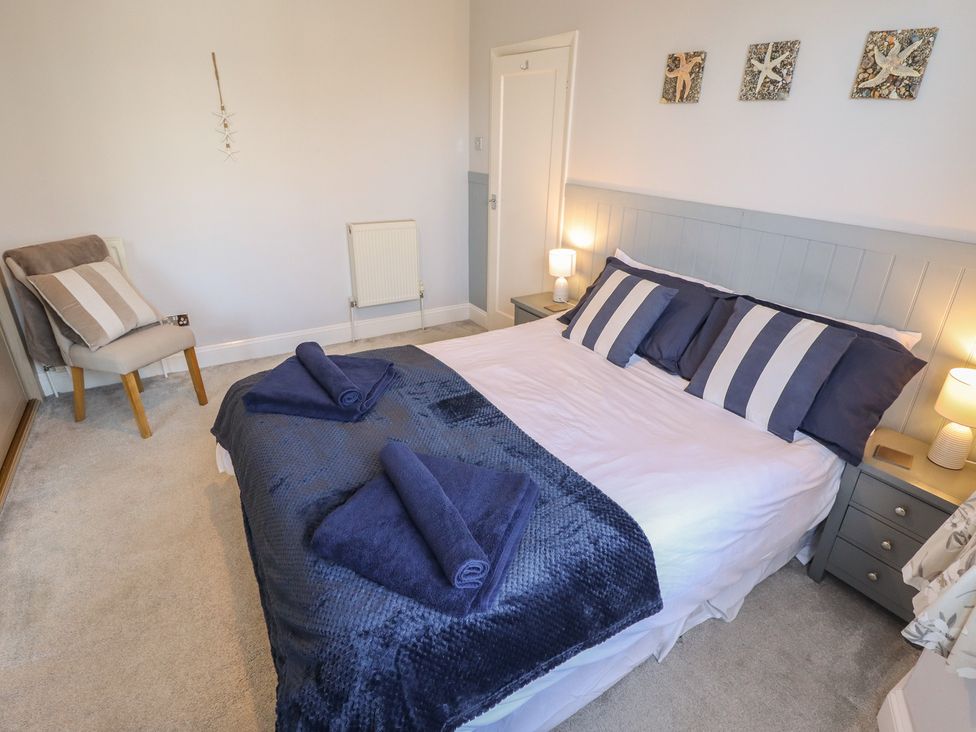 A bedroom with a bed and chair at The Seaside Retreat in Sutton-On-Sea