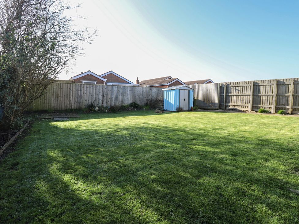 A garden with grass and a shed at The Seaside Retreat in Sutton-On-Sea