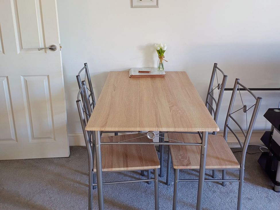 A table with chairs and a vase of flowers at Flat 2 in Ipswich