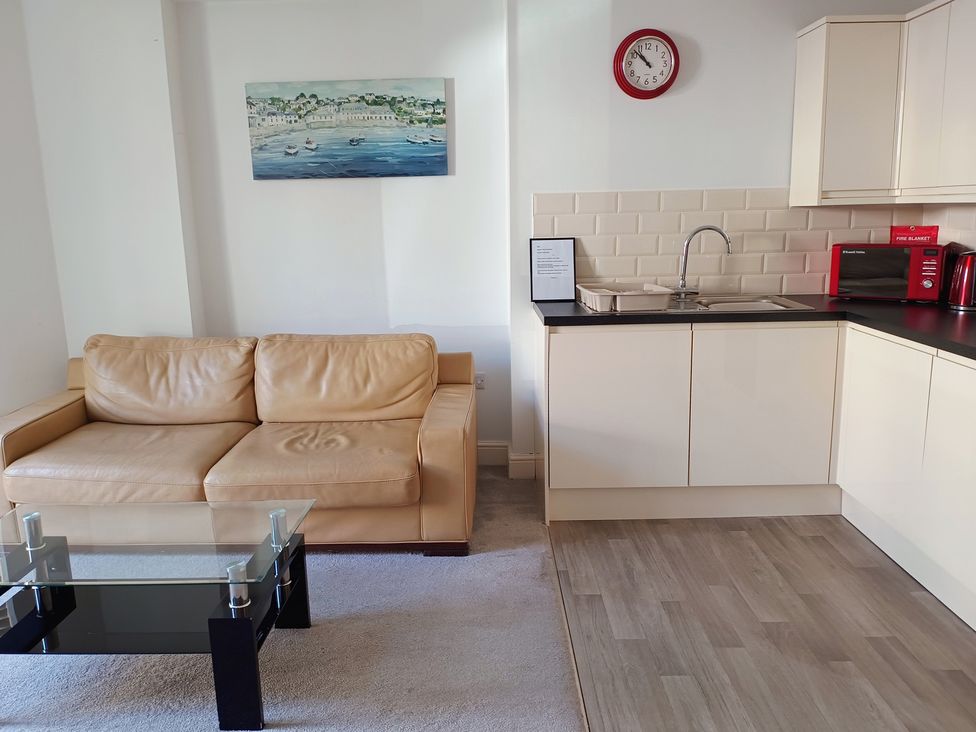 A living room with a sofa and kitchen area at Flat 2 in Ipswich