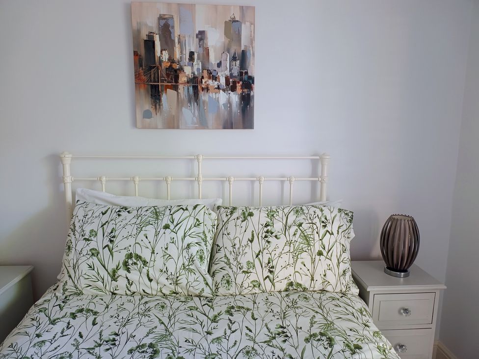 A bedroom with a bed, lamp, and wall art at Flat 2 in Ipswich