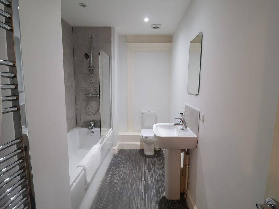 A bathroom with a bathtub, toilet, and sink at Stylish Central Ipswich Apartment Near the Waterfront with Parking in Ipswich