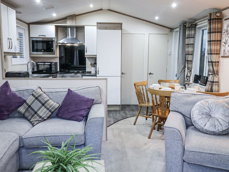 A living room with sofa and dining area at Lakeside Lodge in Stonham Aspal