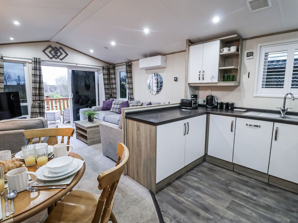 A living room with a kitchen area and dining table at Lakeside Lodge in Stonham Aspal