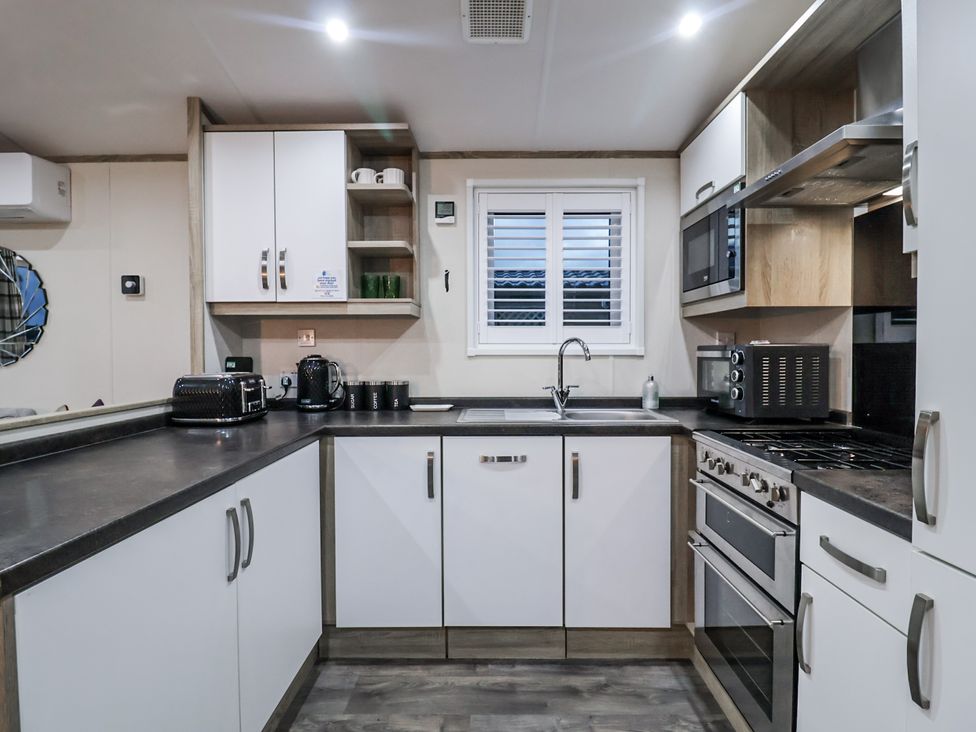 A kitchen with appliances and storage at Lakeside Lodge in Stonham Aspal