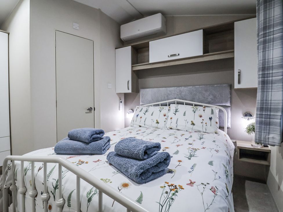 A bedroom with a bed and towels on top at Lakeside Lodge in Stonham Aspal