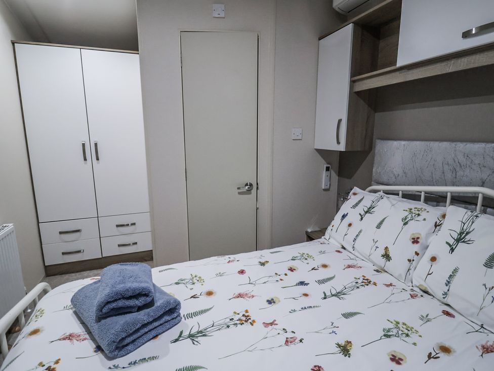 A bedroom with a bed and wardrobe at Lakeside Lodge in Stonham Aspal