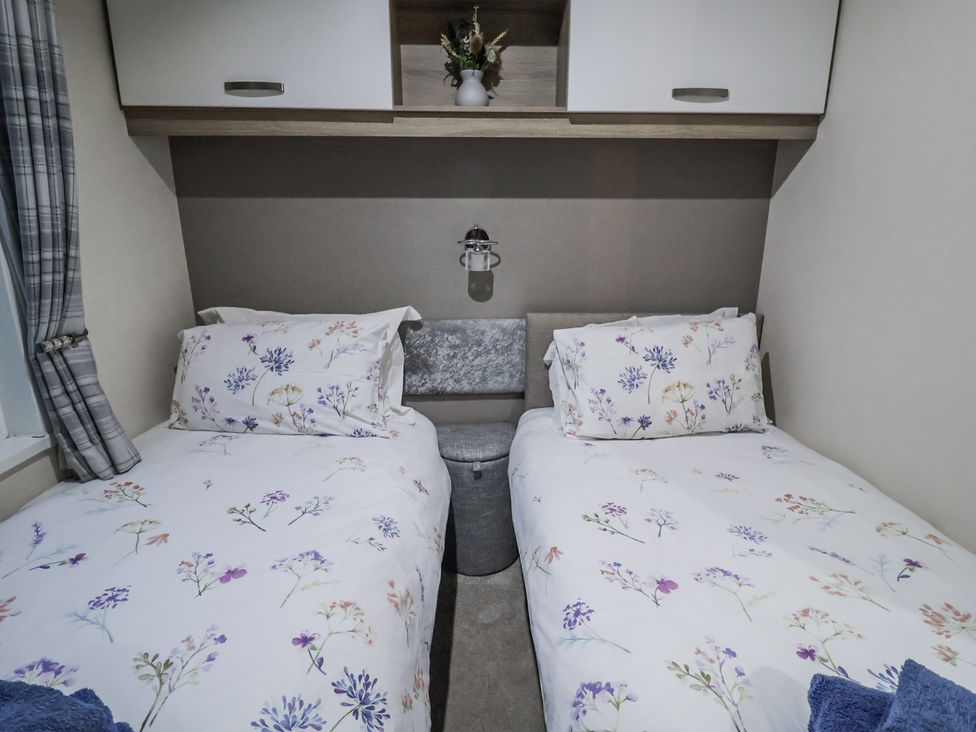 A bedroom with twin beds and a lamp at Lakeside Lodge in Stonham Aspal