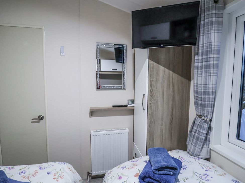 A bedroom with a mirror and television at Lakeside Lodge in Stonham Aspal