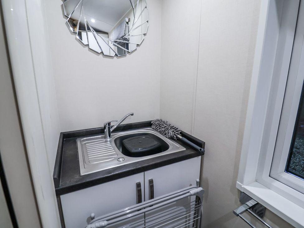 A laundry room with a sink and mirror at Lakeside Lodge in Stonham Aspal