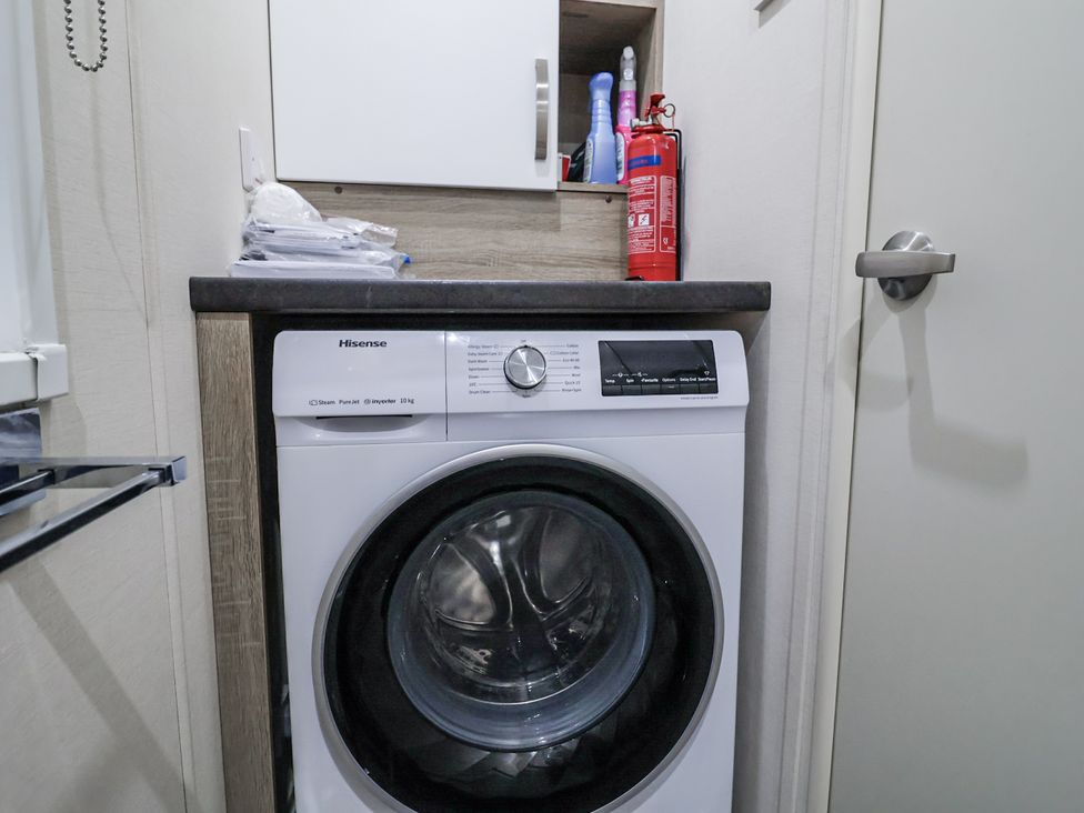 A laundry room featuring a washing machine and cleaning supplies at Lakeside Lodge in Stonham Aspal