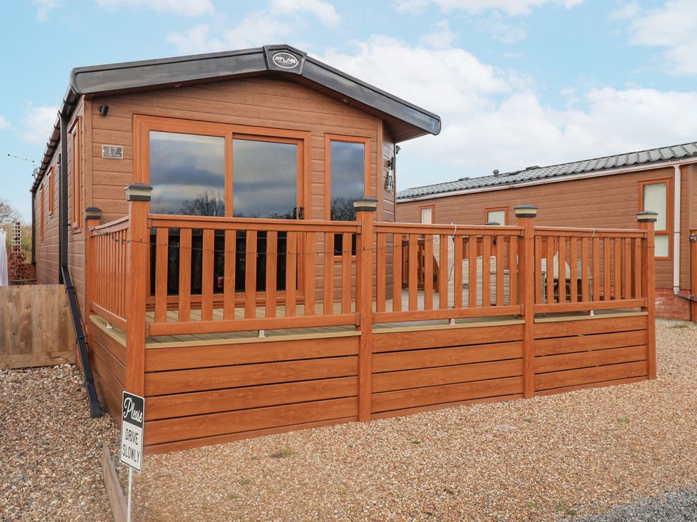 A cabin with a deck and windows at Lakeside Lodge in Stonham Aspal