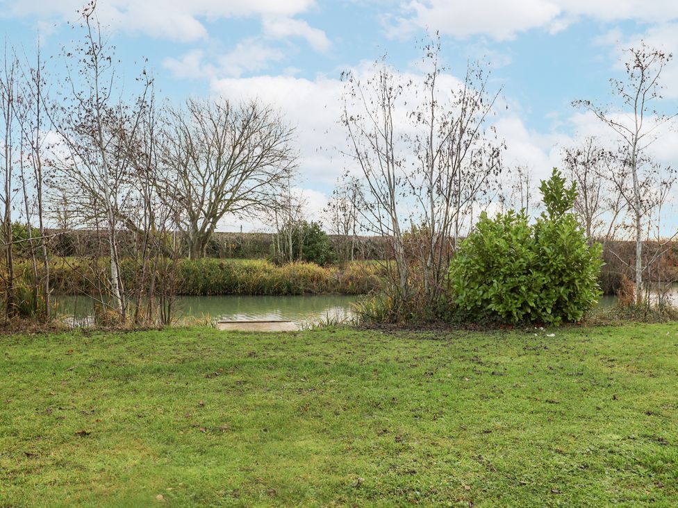 A view of a pond with grass and trees at Lakeside Lodge in Stonham Aspal