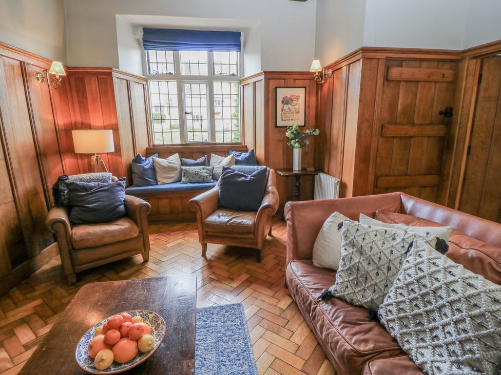 A living room with sofa, armchairs, and a table at Ostlers, Burford