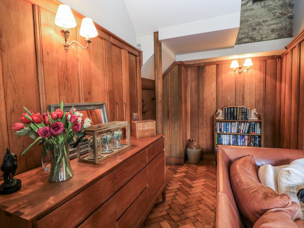 A living room with a wooden dresser and flowers at Ostlers in Burford