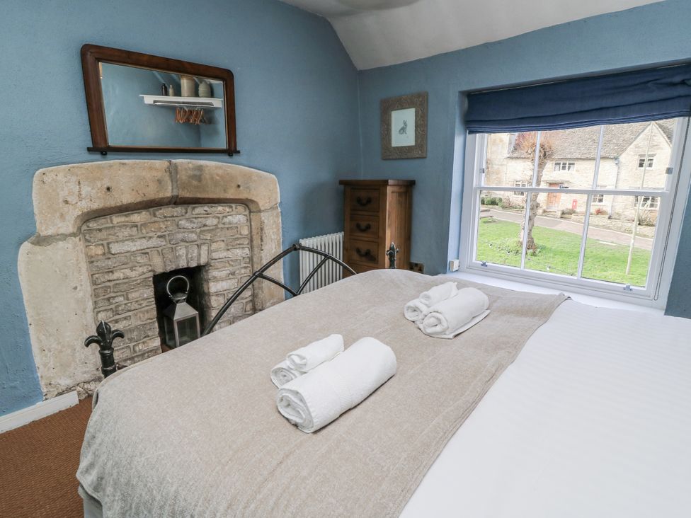 A bedroom with a bed and a fireplace at Ostlers in Burford