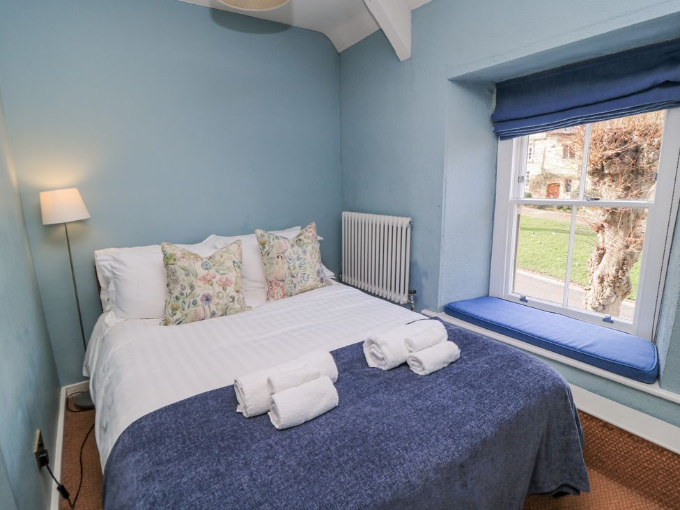 A bedroom with a bed and window seat at Ostlers Burford