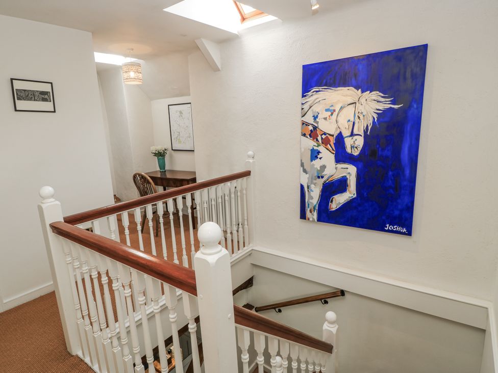 A staircase with a painting and a table with a chair at Ostlers in Burford