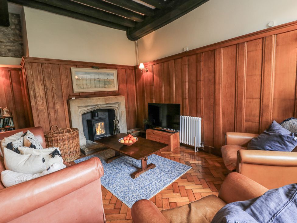 A living room with a fireplace and sofa at Ostlers in Burford
