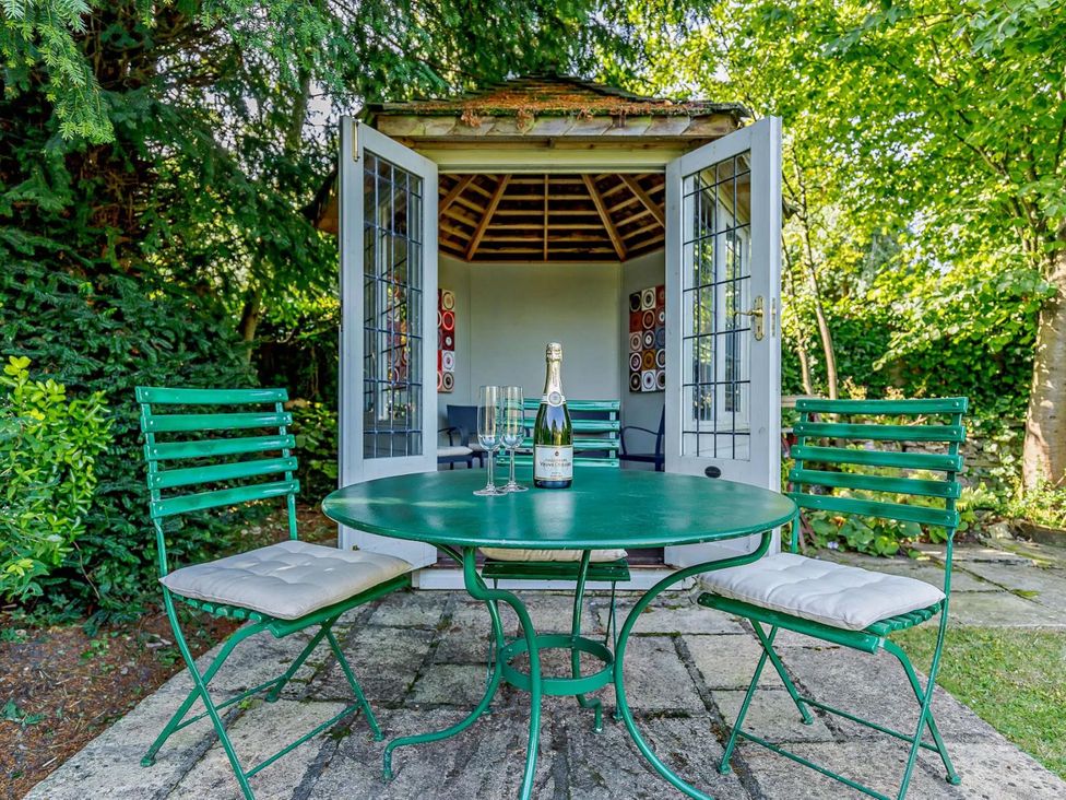 A table with chairs and a champagne bottle outside a shed at Ostlers Burford