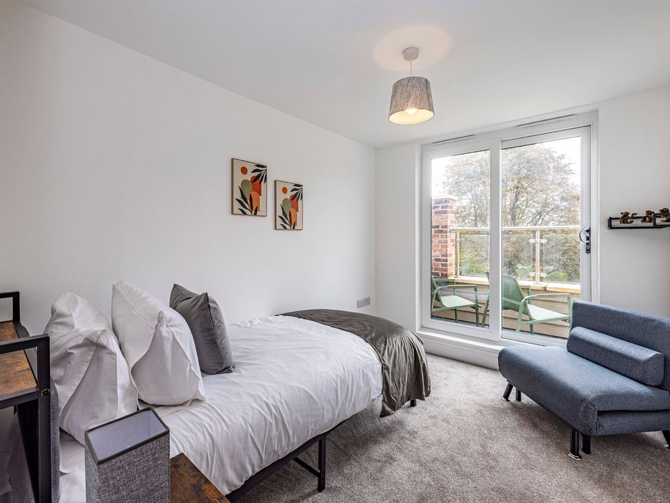 A bedroom with a bed and sofa at 3 Riverside Mews Derby