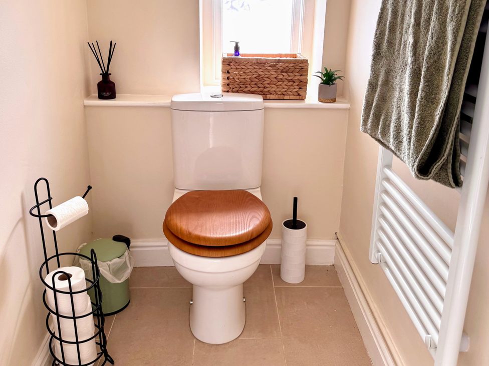A toilet with a wooden seat and towel rail in a bathroom at Cotswolds Farmhouse Cottage