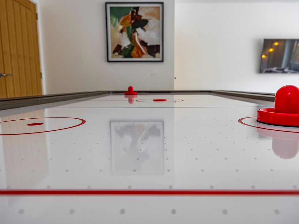 An air hockey table with a puck and wall art at 6 Riverside Mews in Derby