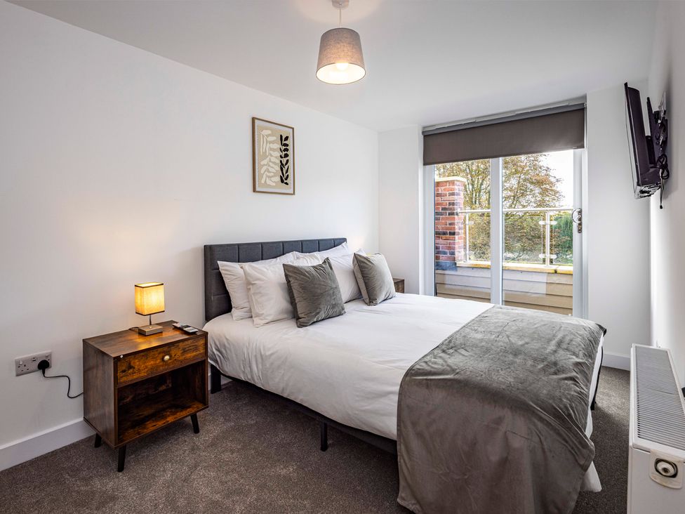A bedroom with a bed and a nightstand at 6 Riverside Mews in Derby