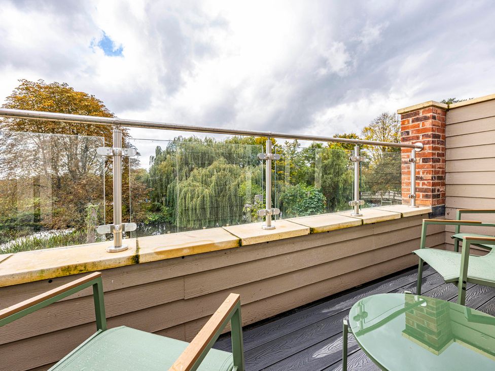 A balcony with a table and chairs overlooking trees at 6 Riverside Mews Derby