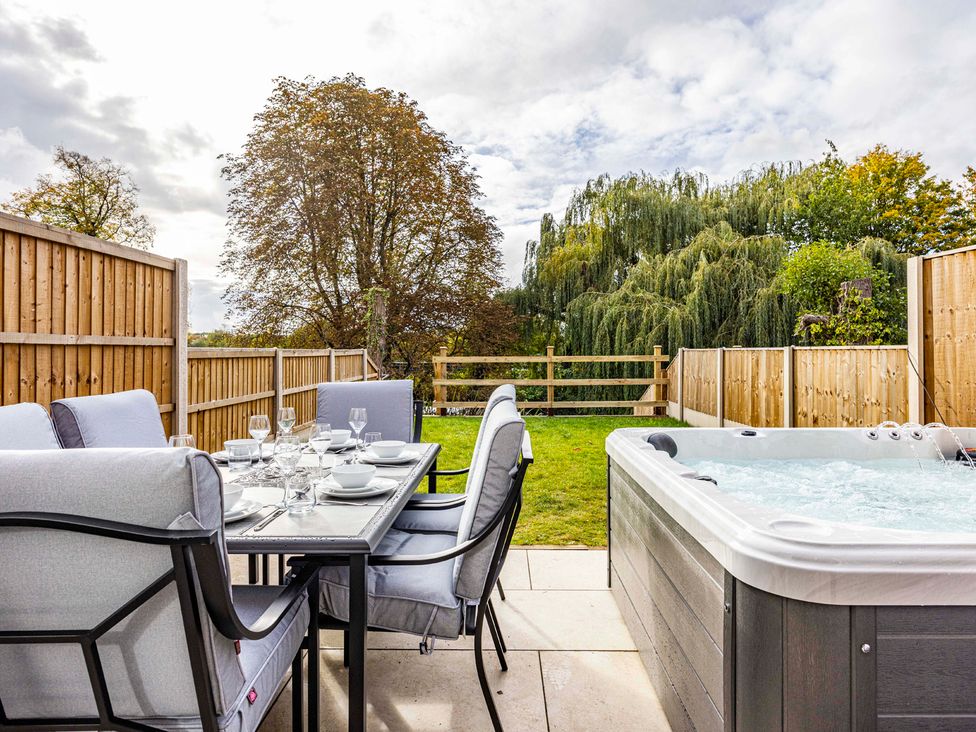 An outdoor area with a dining table and chairs next to a hot tub at 6 Riverside Mews in Derby