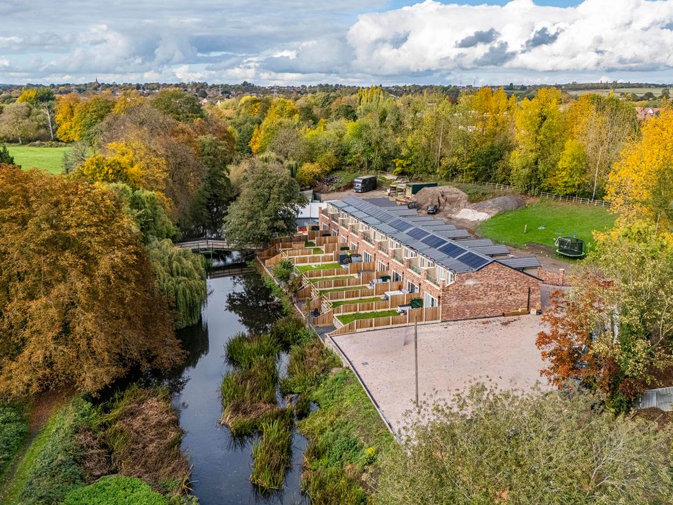 An outdoor view of buildings by a river and trees at 6 Riverside Mews Derby