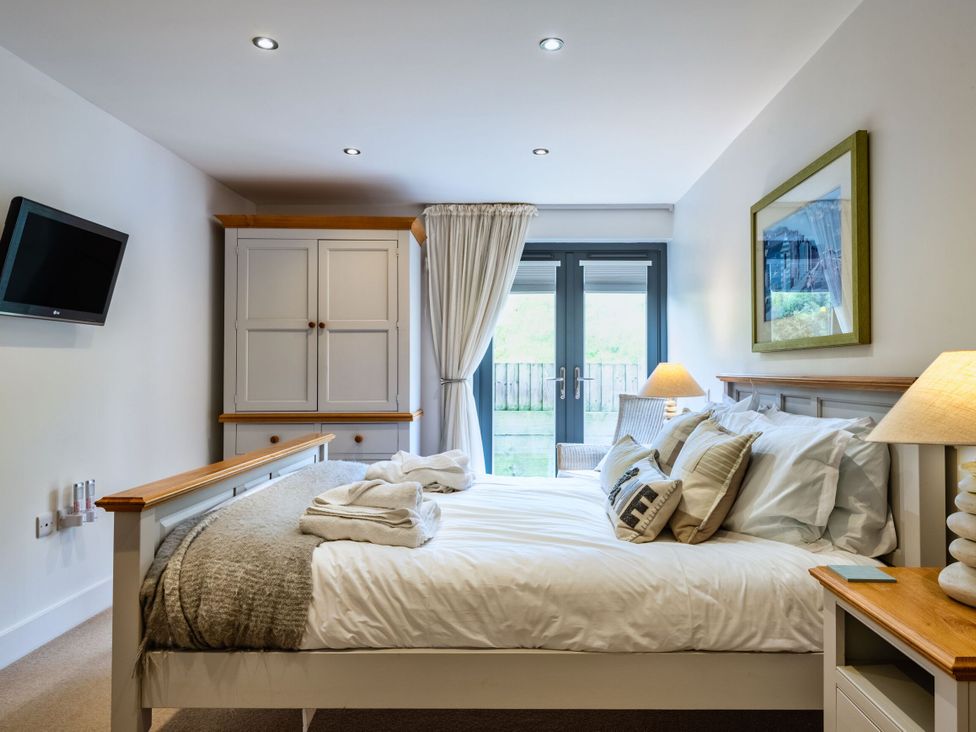 A bedroom with a bed and wardrobe at Beachcombers in Marhamchurch