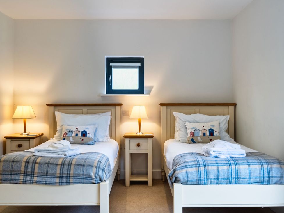 A bedroom with two beds and lamps at Beachcombers in Marhamchurch