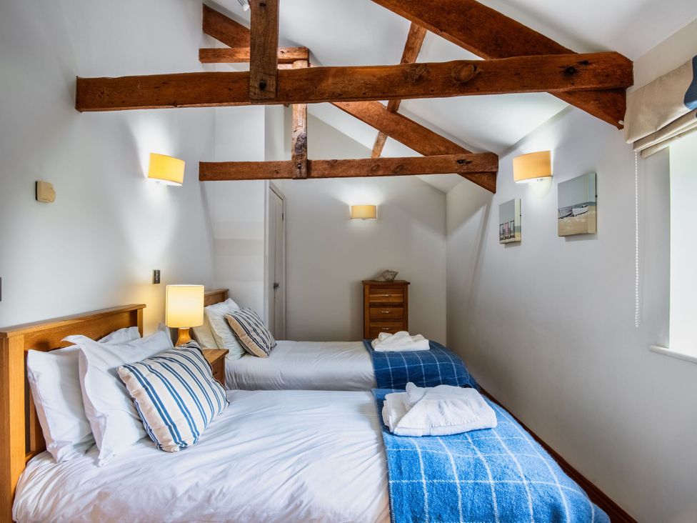 A bedroom with two beds and a nightstand at Woodyplatt in Marhamchurch
