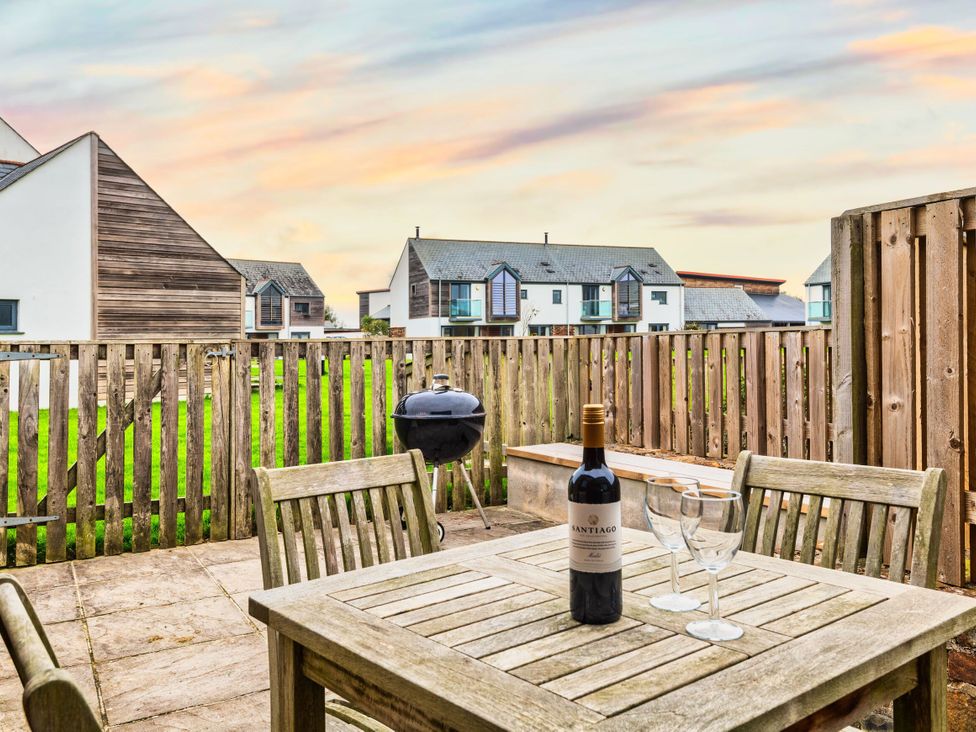 An outdoor area with a table and wine at Woodyplatt in Marhamchurch