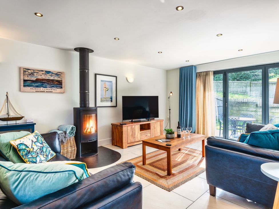 A living room with a fireplace and a television at Chapel Park in Marhamchurch