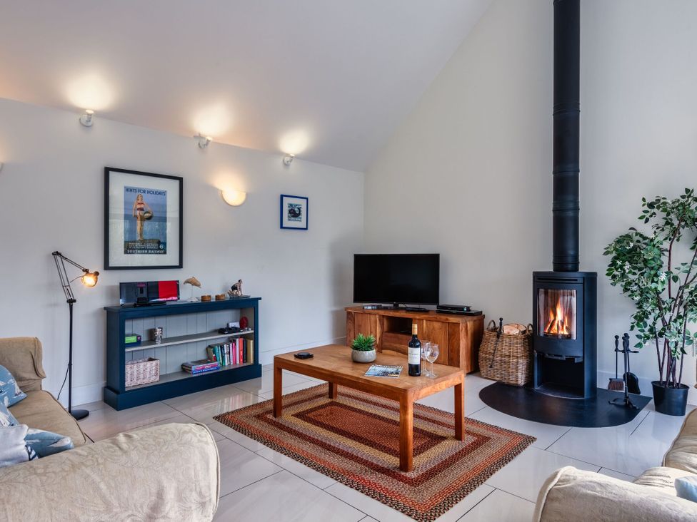 A living room with a sofa, coffee table, and fireplace at Little Main in Marhamchurch