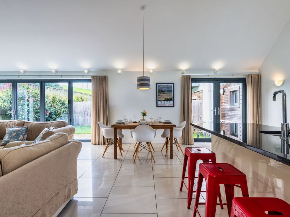 A dining table with chairs and a kitchen bar at Little Main in Marhamchurch