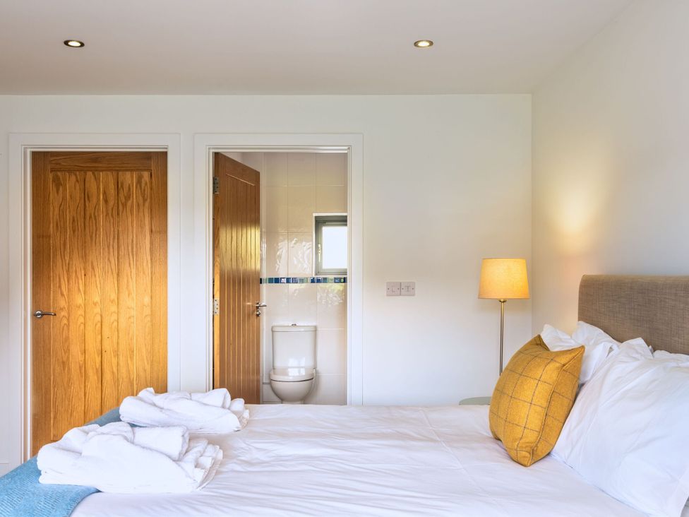 A bedroom featuring a bed and a door leading to a toilet at Little Main in Marhamchurch