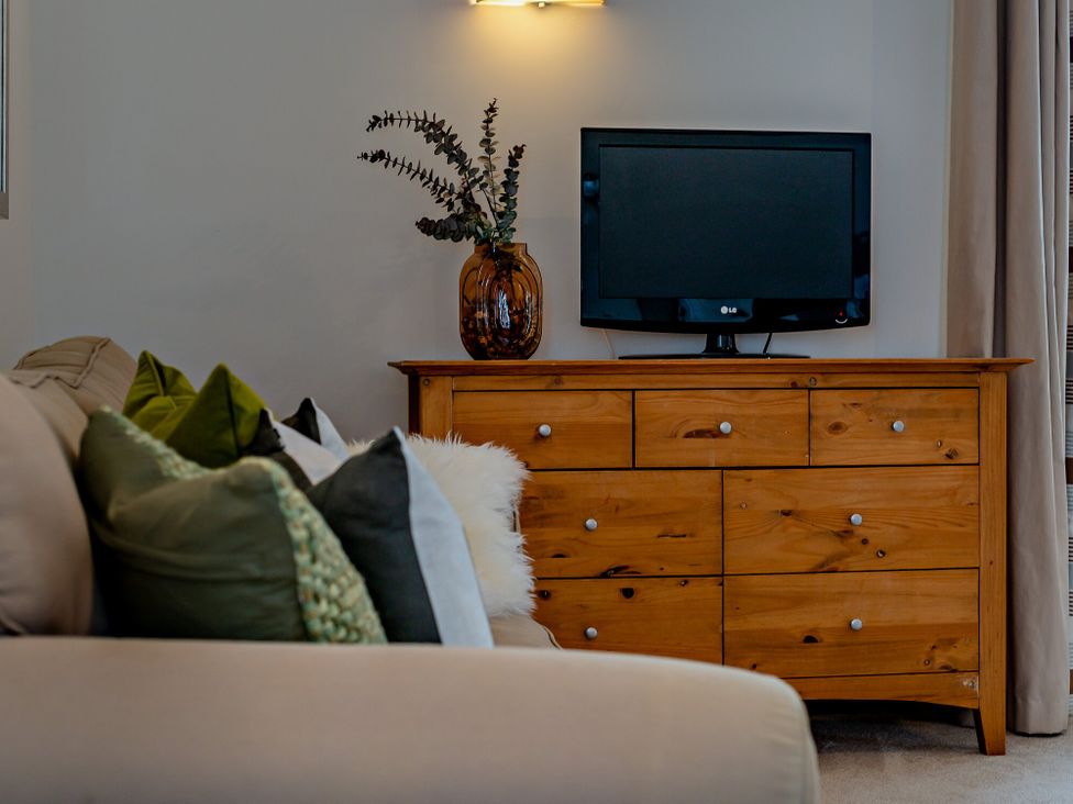 A living room with a sofa and TV at Long Down Spa in Marhamchurch