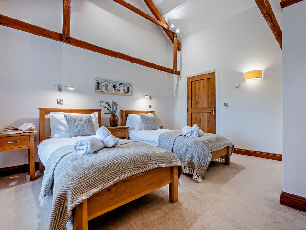 A bedroom with two beds and wooden furniture at Long Down Spa Marhamchurch
