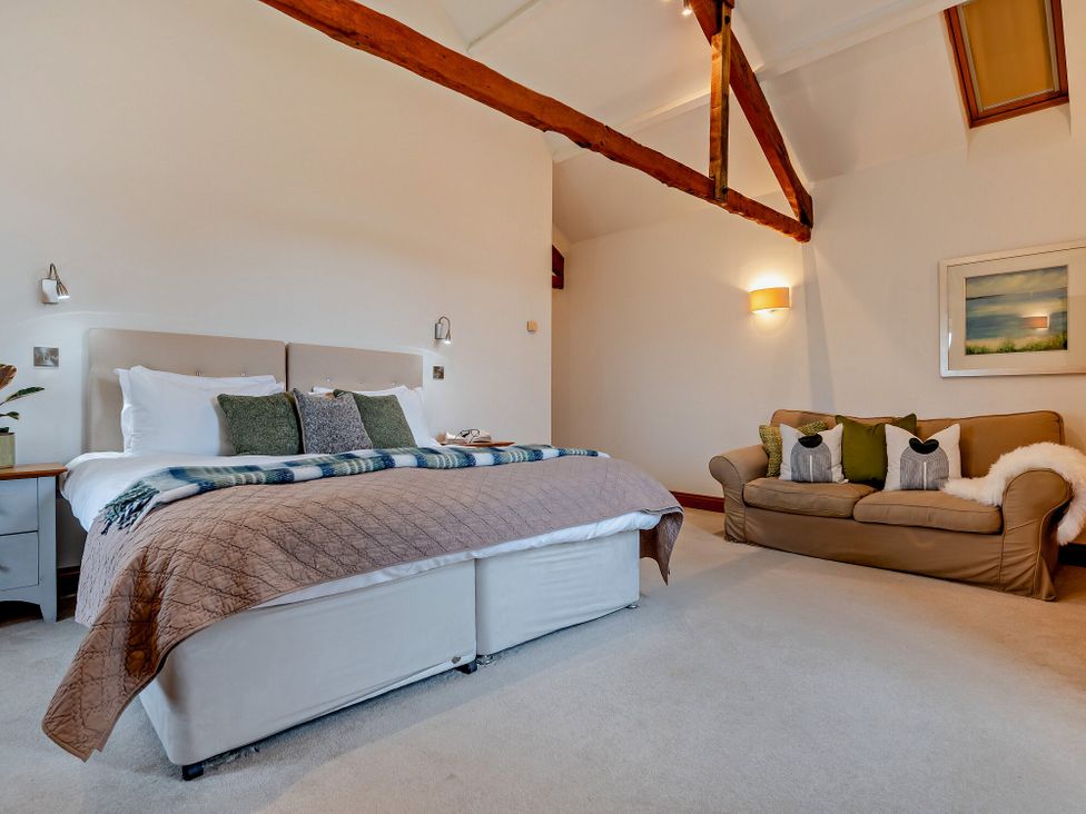 A bedroom with a bed and a sofa at Long Down Spa in Marhamchurch