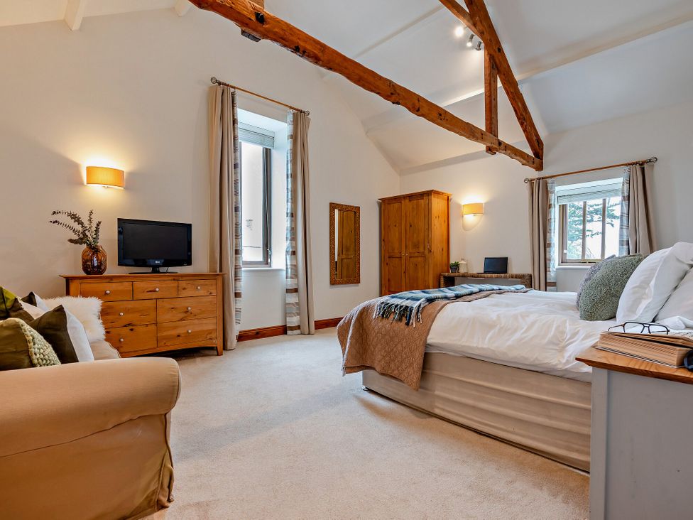 A bedroom with a bed, television, and wardrobe at Long Down Spa in Marhamchurch