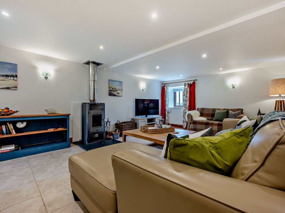A living room with a stove and sofa at Middle Hill in Marhamchurch